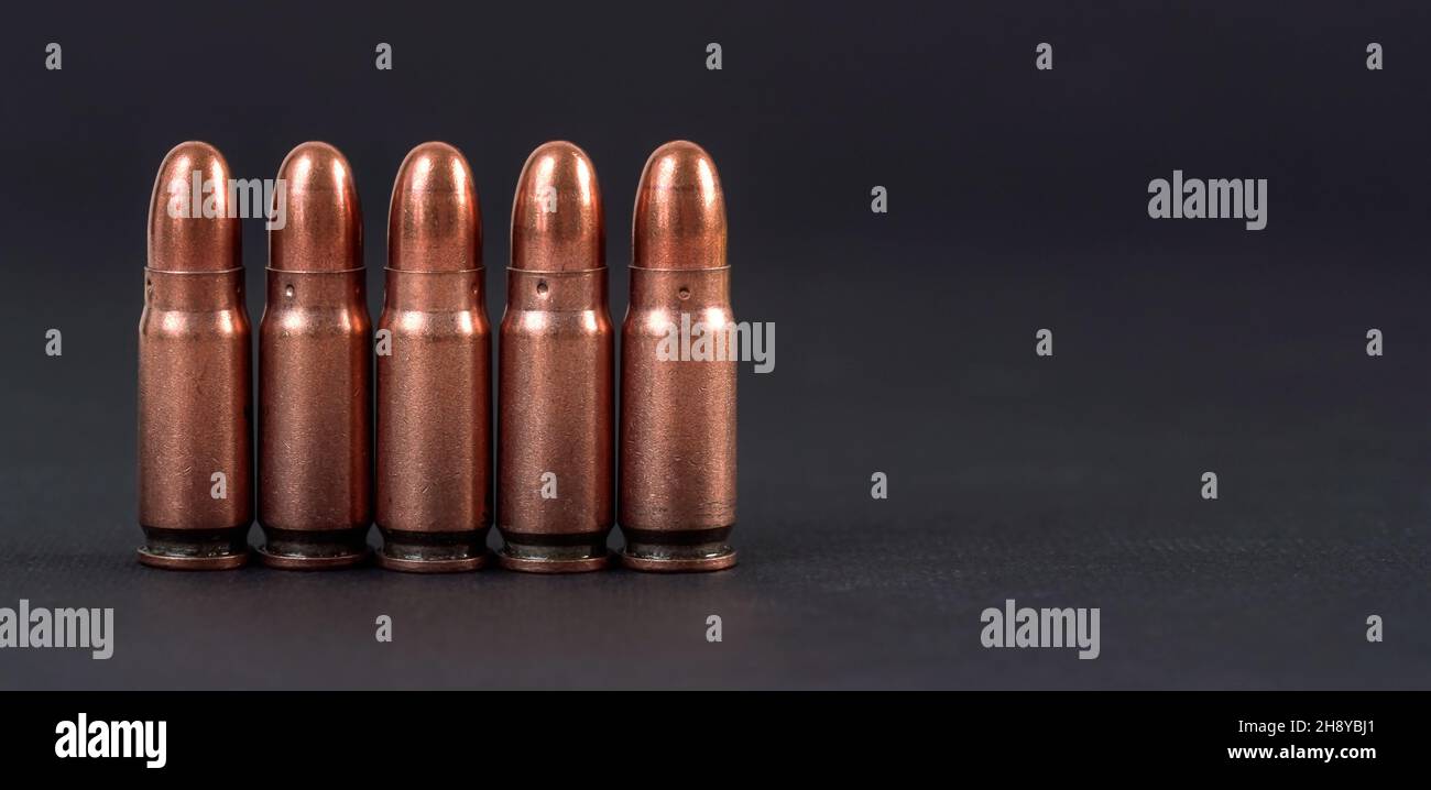 Cinco balas de pistola de bronce dispuestas una junto a la otra en pizarra  negra, espacio para texto en el lado derecho Fotografía de stock - Alamy