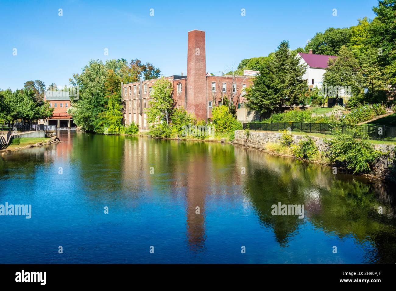 Laconia, New Hampshire, Estados Unidos de América – 16 de septiembre de 2016. Vista a través de las aguas del embalse de Opechee Bay hacia el edificio histórico con chimenea, Foto de stock