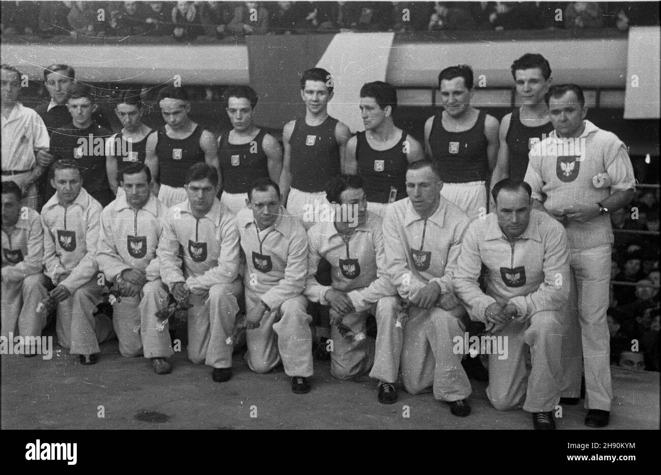 Warszawa, 1947-02-02. Mecz bokserski Polska - Czechos³owacja (12:4) w hali toru wyœcigowego na S³u¿ewcu. od lewej, klêcz¹: Wawrzyniec Bazarnik - waga musza, Maksymilian Grzywocz - waga kogucia, Stanis³aw Leczkowski - waga piórkowa, E. Sowiñski - waga lekka, Jerzy Olejnik - waga pó³œrednia, Antoni Kolczyñski - waga œrednia, Franciszek Szymoka - waga pó³ciê¿ciê¿stoj¹ Sekundant polskiej dru¿yny Feliks Stamm, Ota Rademacher - waga ciêzka, Cda - waga pó³ciê¿ka, Julius Torma - waga œrednia, Oldrich Koudela - waga pó³œrednia, Griga - waga lekka, Macela - w Foto de stock