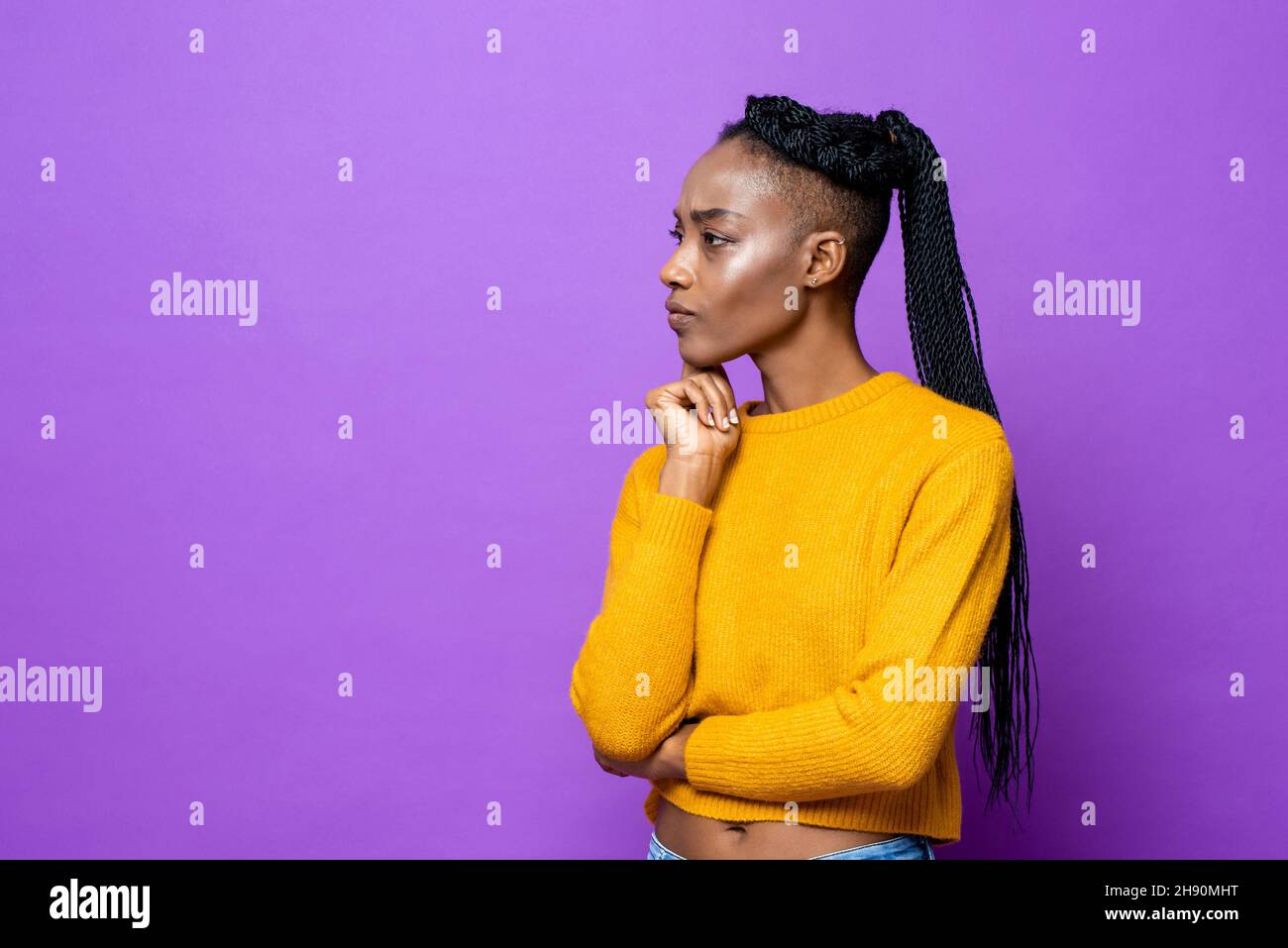 Mujer joven afroamericana pensando con la mano en la barbilla en un fondo de estudio aislado de color púrpura Foto de stock
