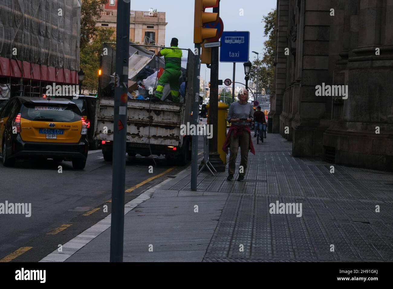 Barcelona, España - 5 de noviembre de 2021: Camión de basura en la calle, los trabajadores tiran basura, Editorial ilustrativa. Foto de stock