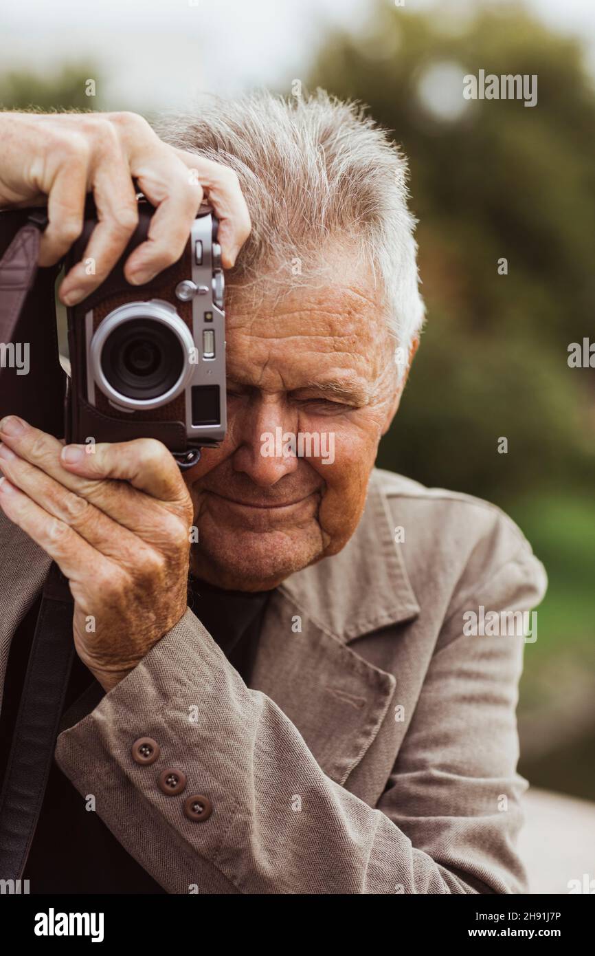 Hombre anciano fotografiando a través de la cámara durante las vacaciones Foto de stock
