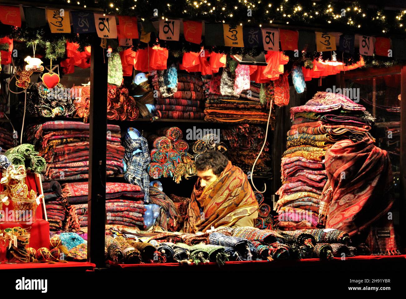 EDIMBURGO, ESCOCIA - 18 DE DICIEMBRE de 2019: El trabajador de la cabina en el mercado de Navidad de Edimburgo se ahora para el calor en algunos de los bufandas que están vendiendo. Foto de stock
