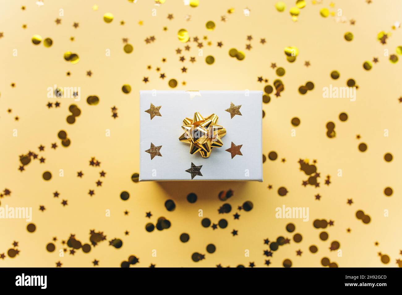 Caja blanca de regalo con cinta dorada con piel y confeti sobre fondo blanco. El concepto de un regalo, un año nuevo, un fondo festivo. Plano, vista superior. Foto de stock