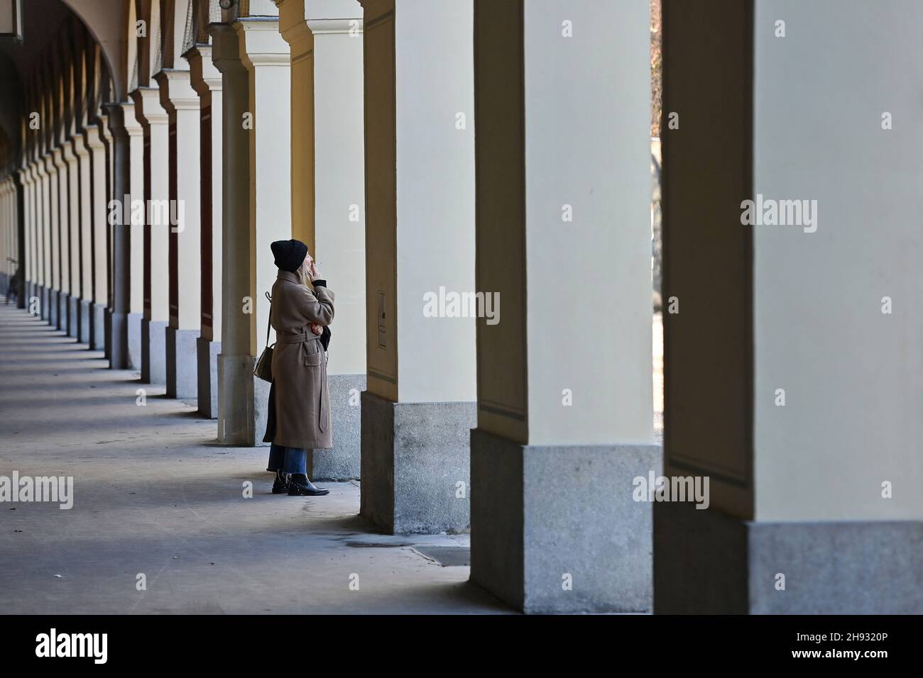 Munich, Alemania. 03rd de Dic de 2021. Tema de la soledad de la imagen. Una mujer está de pie fumando en las arcadas del Hofgarten en Munich y mira hacia fuera después. Crédito: dpa/Alamy Live News Foto de stock