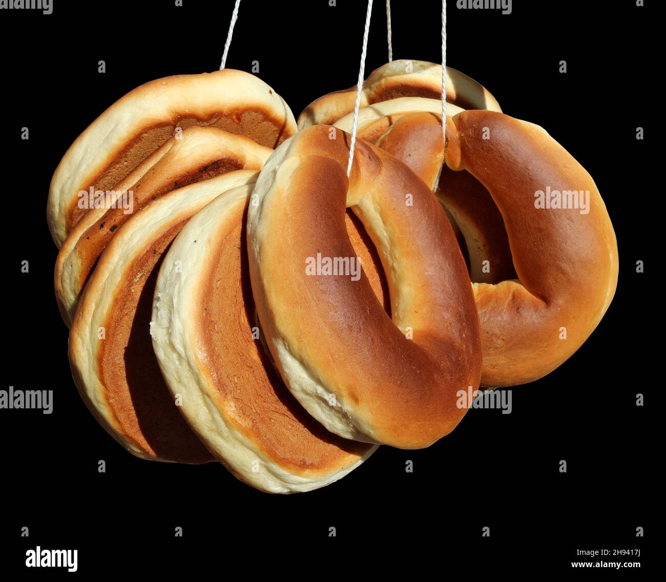 Tradicionales rosquillas de bagel folk en forma de anillos sobre una cuerda. Aislado sobre negro Foto de stock