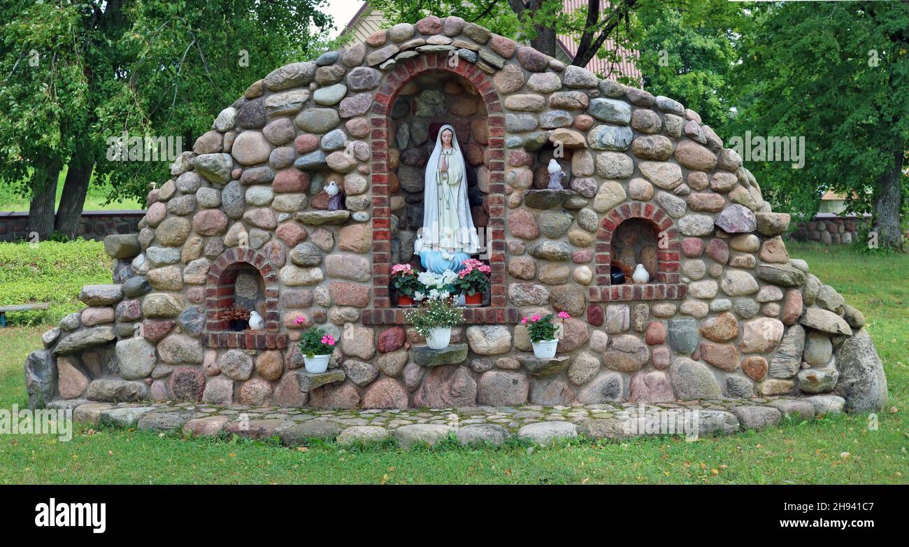 SILENAI, LITUANIA - 01 DE AGOSTO de 2021: Monumento a la Santísima Virgen María cerca de la iglesia católica rural construida de grandes piedras de granito. La iglesia era Foto de stock