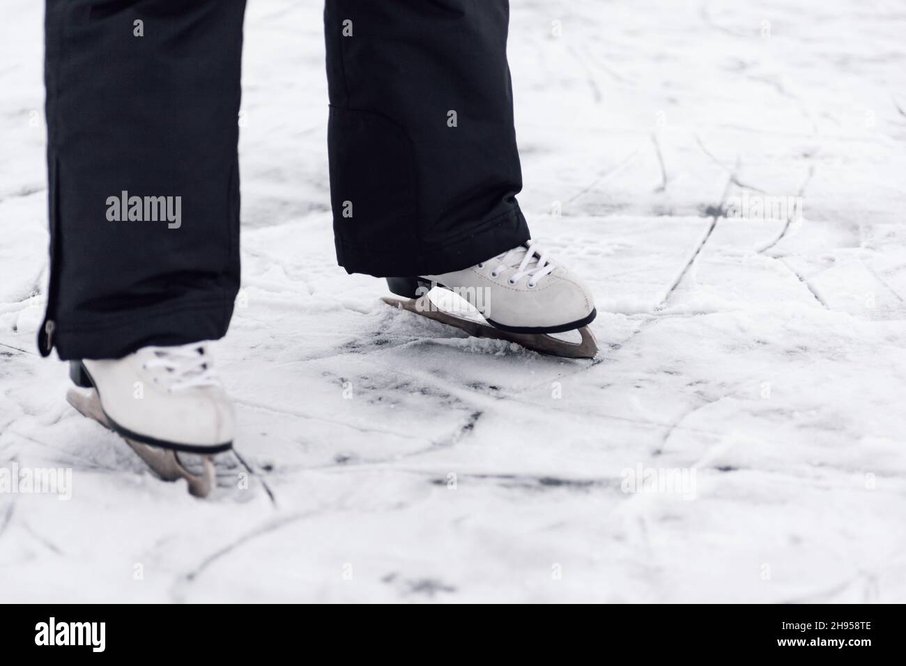 Patinetas de patinaje. Primer plano de las piernas del hombre en pantalones  negros de invierno de pie sobre hielo de lago congelado en patines de  patinaje de figura blanca Fotografía de stock -
