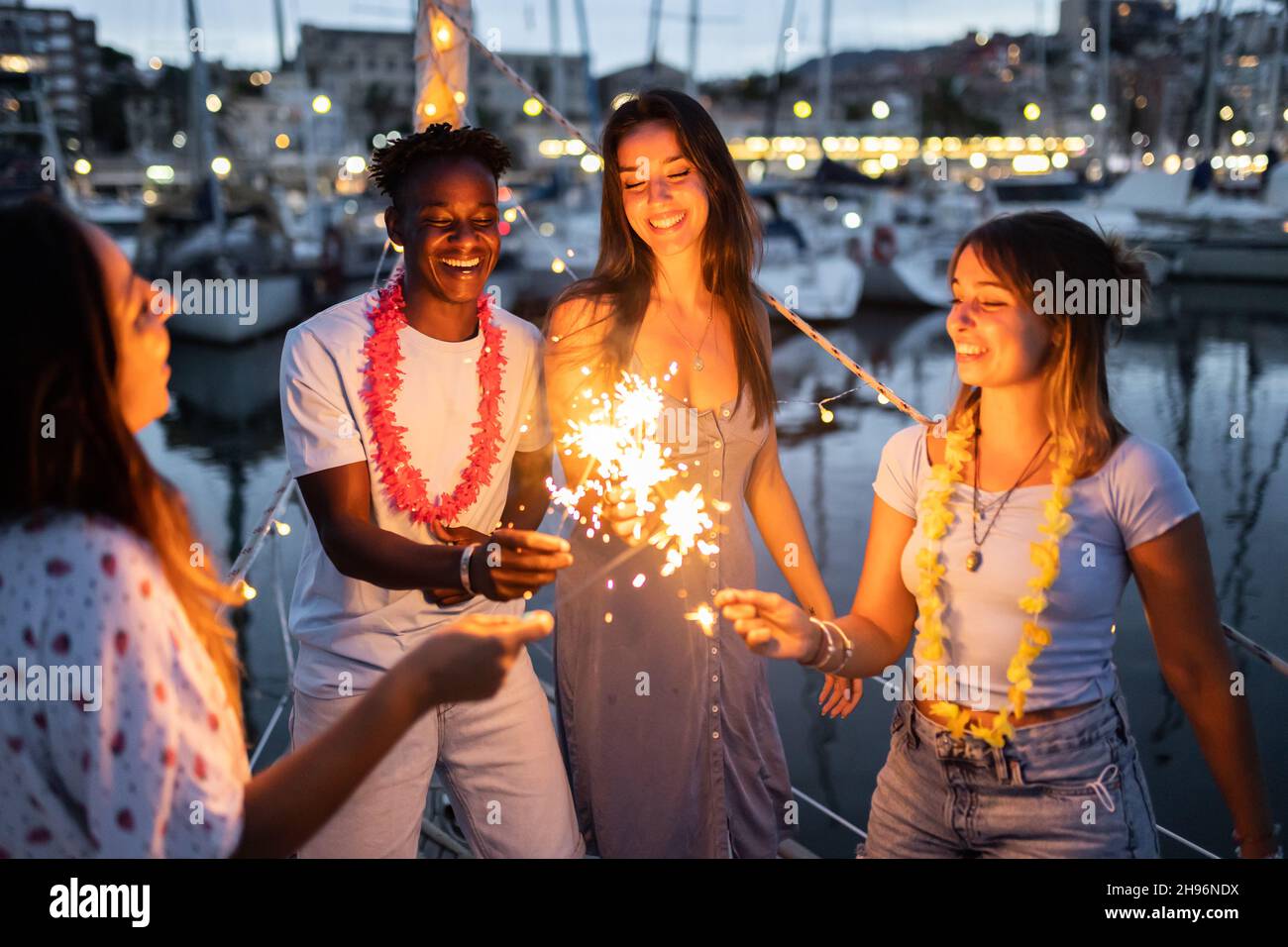 Amigos multirraciales celebrando la víspera de Año Nuevo en un barco en un país del caribe - Enfoque en el tipo afroamericano Foto de stock