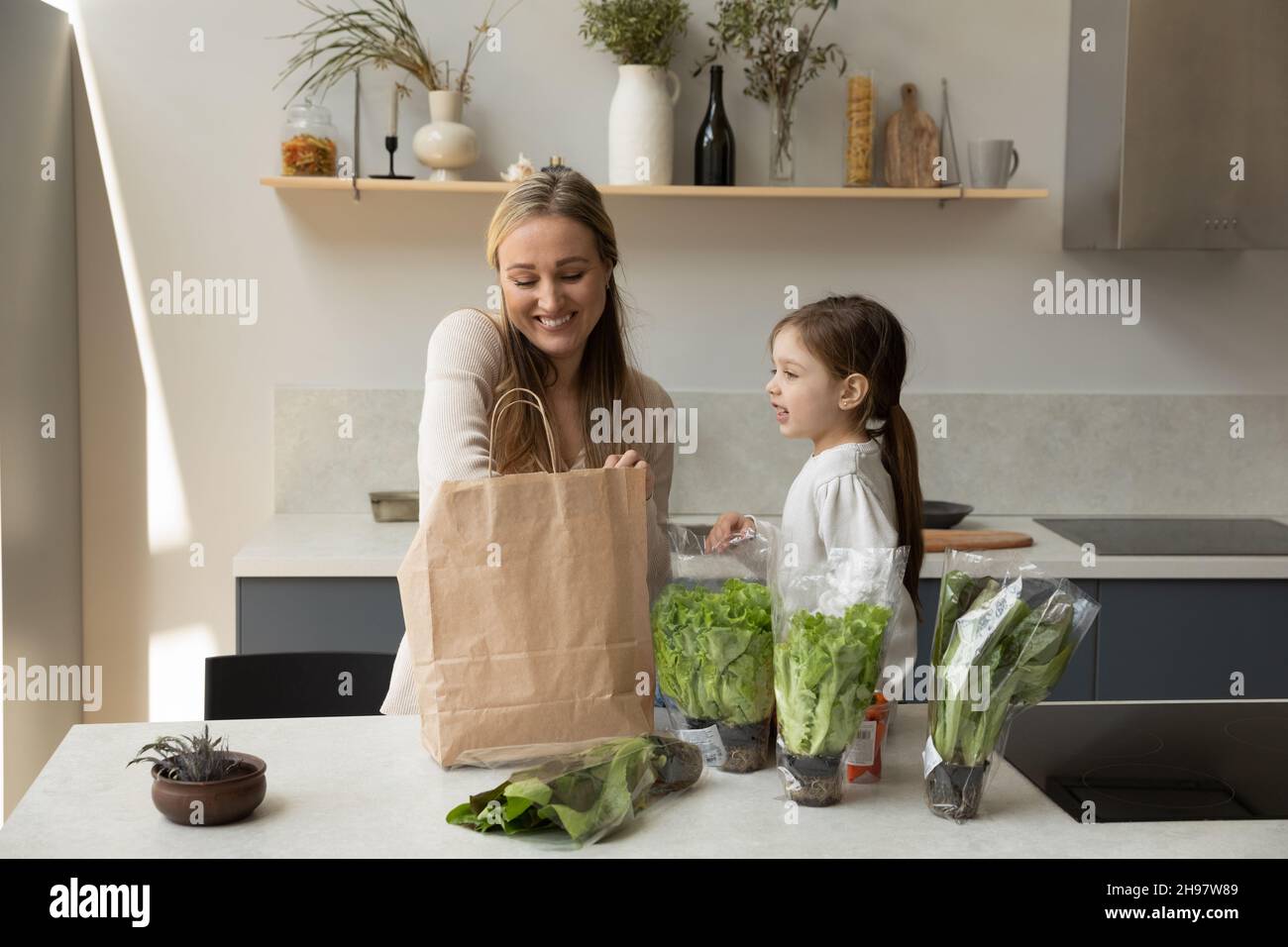 Feliz madre joven y niño desempacando productos. Foto de stock