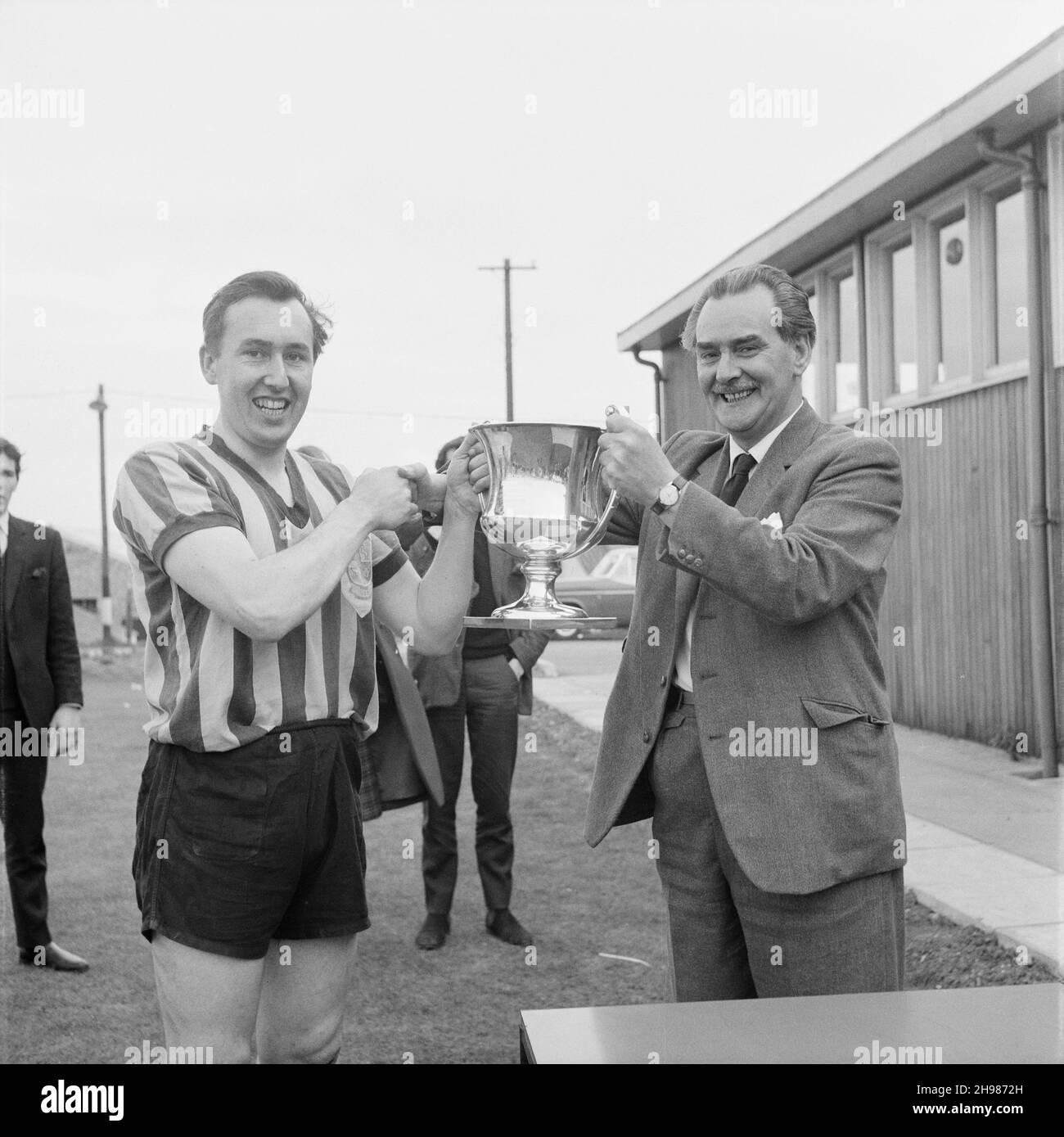 Peter Hipkin, capitán del equipo de fútbol 1st del Laing Sports Club, 27/04/1963. Peter Hipkin, capitán del equipo de fútbol de 1st del Laing Sports Club, será presentado por V Ball, Vicepresidente de la Liga Comercial de Londres, con la Senior Challenge Cup. Esta imagen fue publicada en junio de 1963 en el boletín mensual de Laing 'Team Spirit'. La Sección de Fútbol del Laing Sports Club había tenido una temporada muy exitosa, con el equipo de 1st ganando cada uno de sus juegos. Foto de stock