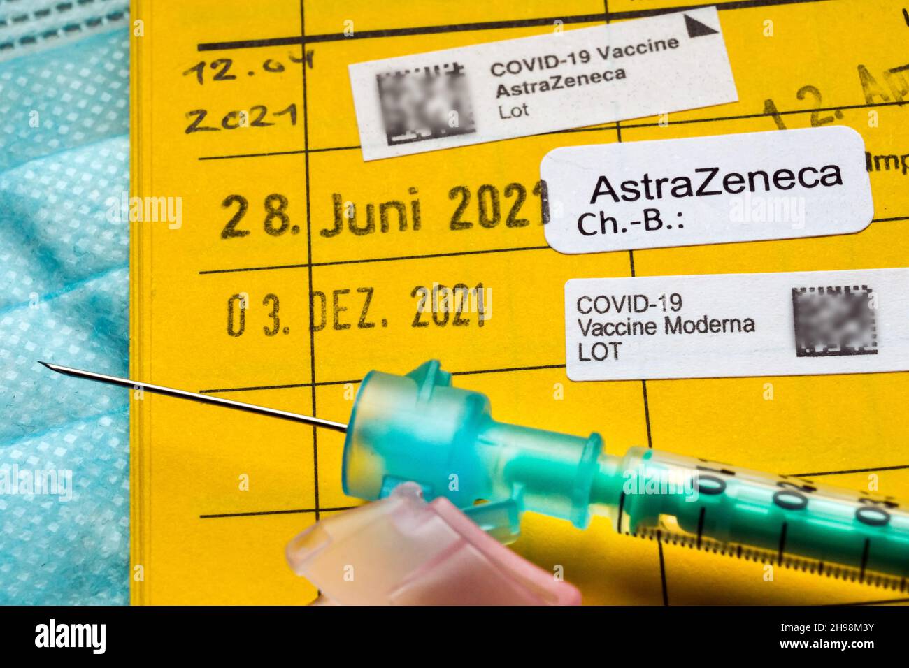 Jeringa en una tarjeta de vacunación alemana con la nota de tres vacunas contra Covid-19, vacuna de refuerzo - 5 de diciembre de 2021 --- Spritze auf einem Impfausweis mit dem Einag von drei Impfungen gegen Covid-19, Booster-Impfung - 5.12.2021 Foto de stock