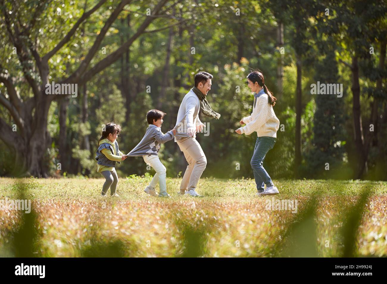 familia asiática joven con dos niños divirtiéndose jugando al aire libre en el parque Foto de stock