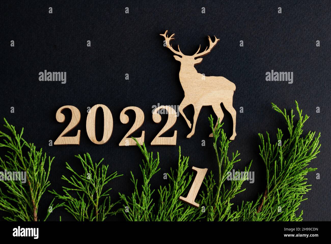 2022, composición de navidad sobre fondo negro, ciervo de madera, espacio de copia Foto de stock