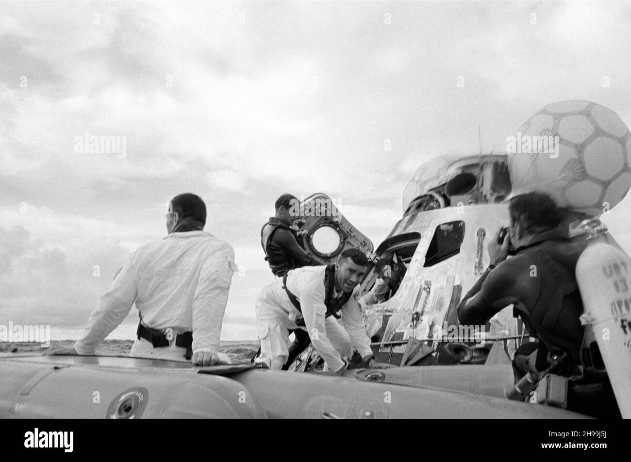 Vista del nivel del agua de las operaciones de recuperación de Apollo 13 en el Océano Pacífico Sur. A los tres astronautas se les ve a la salida de su nave espacial. John L. Swigert Jr. (De vuelta a la cámara), piloto de módulo de mando, ya está en la balsa de la vida. Fred W. Haise Jr., piloto del módulo lunar, frente a la cámara, está entrando en la balsa de la vida. James A. Lovell Jr., comandante, está dejando la nave espacial en el fondo. Un equipo de demolición submarina de la Marina de los Estados Unidos asiste en las operaciones de recuperación. Los tres tripulantes fueron recogidos en helicóptero y volados al buque de recuperación principal, USS Iwo Jima Foto de stock