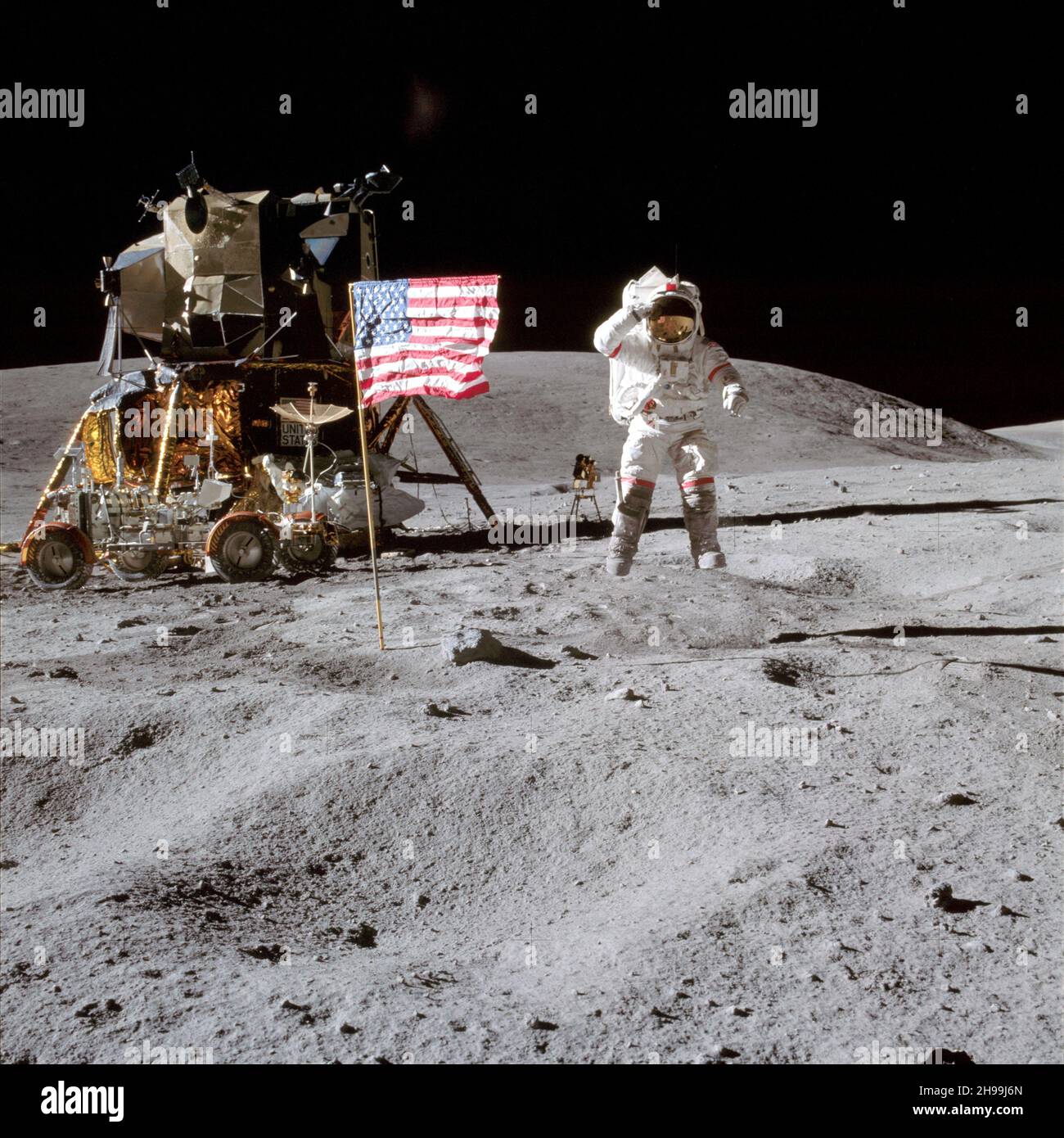 El astronauta John W. Young, comandante de la misión de aterrizaje lunar del Apolo 16, en la superficie lunar mientras saluda la bandera de los Estados Unidos en el lugar de aterrizaje de Descartes durante la primera actividad extrvehicular del Apolo 16 Foto de stock