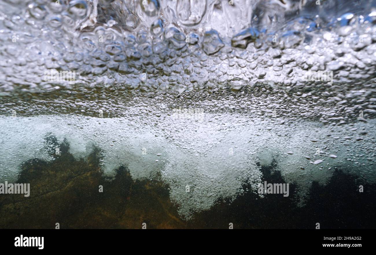 Burbujas de aire bajo la superficie del agua generadas por una cascada en un río, escena natural, España, Galicia Foto de stock
