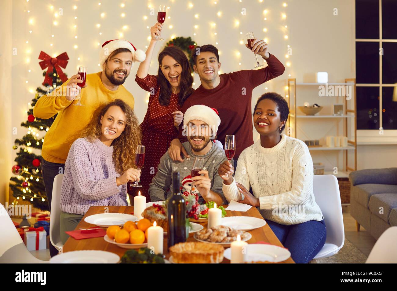 Retrato en grupo de amigos multirraciales felices en la mesa de la cena en la fiesta de Navidad en casa Foto de stock