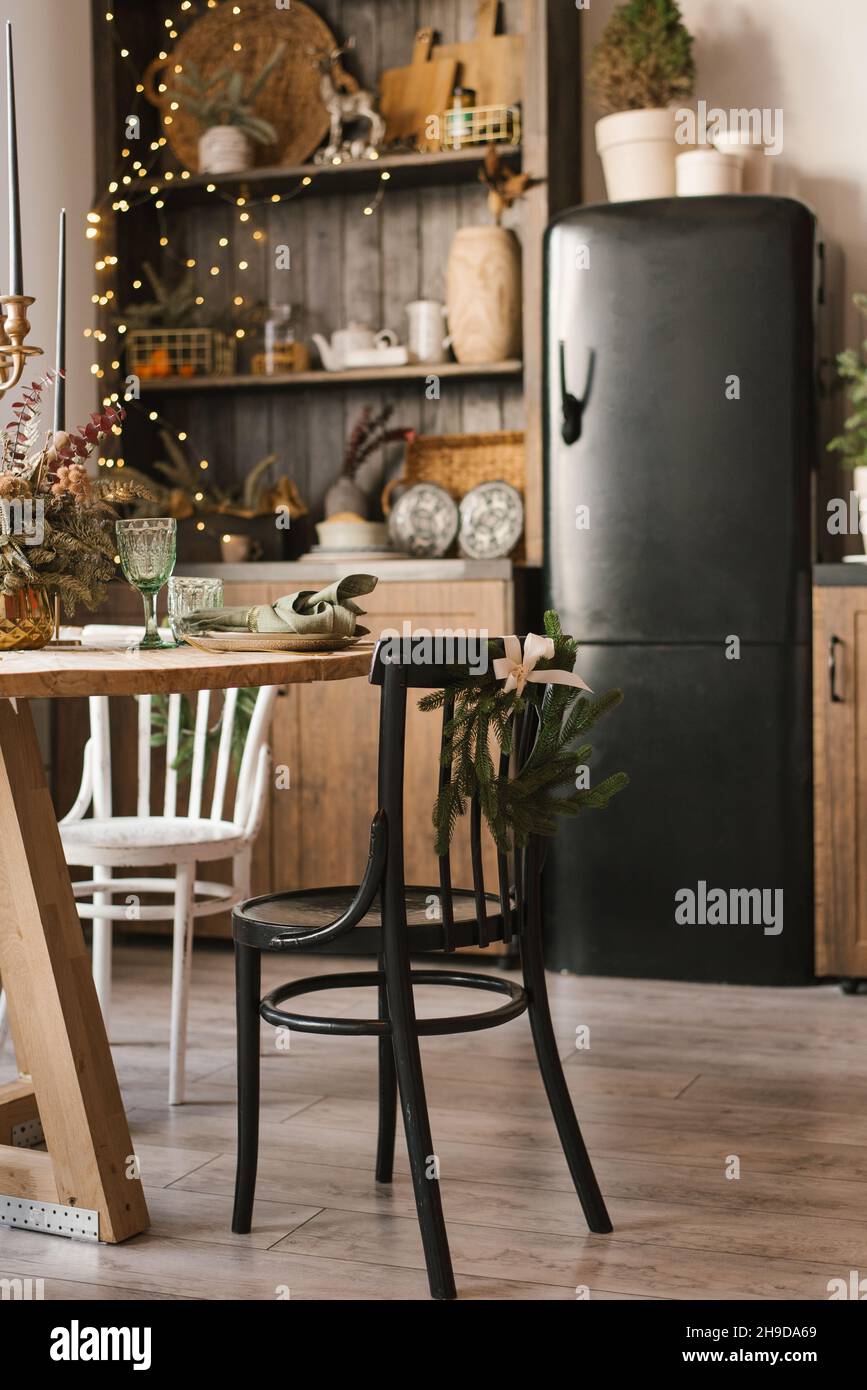 Sala de estar o cocina interior con una mesa de comedor redonda y una  variedad de sillas en una casa de campo decorada para Navidad y Año Nuevo Fotografía  de stock 