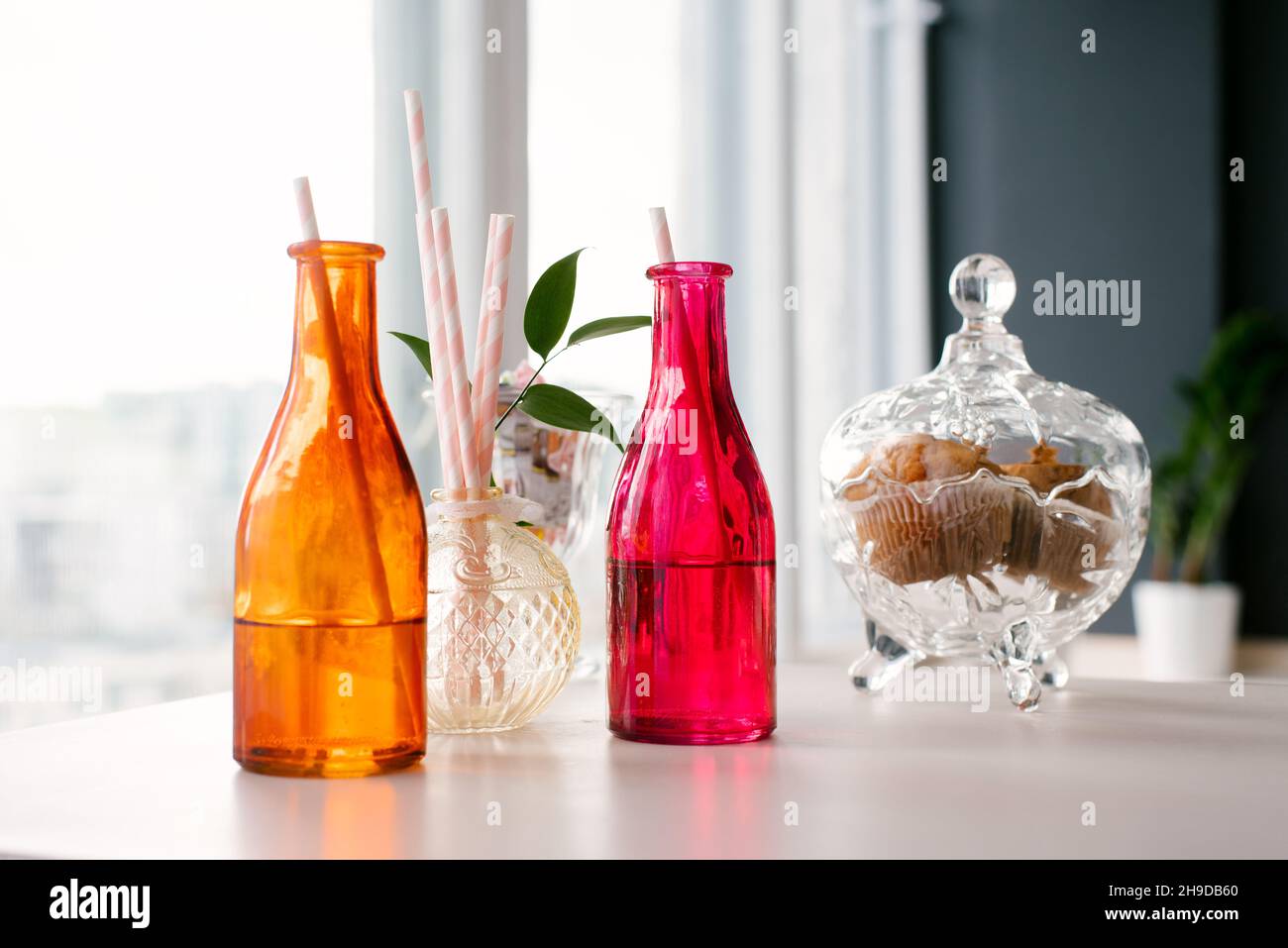 Coloridas botellas de vidrio con pajitas de papel para bebidas o cócteles y  un bol de galletas Fotografía de stock - Alamy