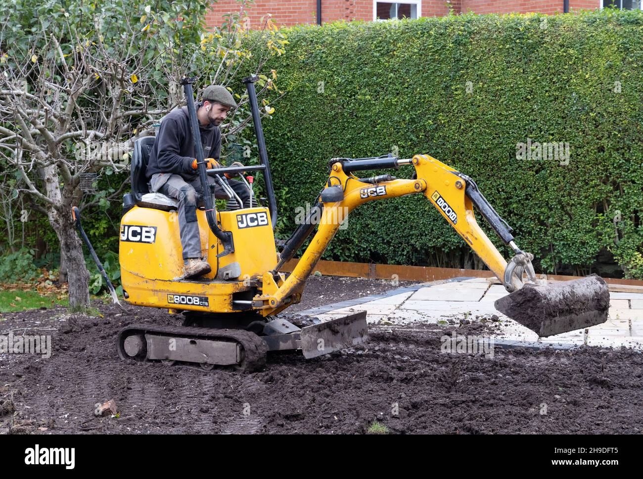 Mano de obra especializada Reino Unido; jardinero paisajista Reino Unido - un hombre que opera un mini digger en un jardín doméstico, Suffolk Reino Unido Foto de stock