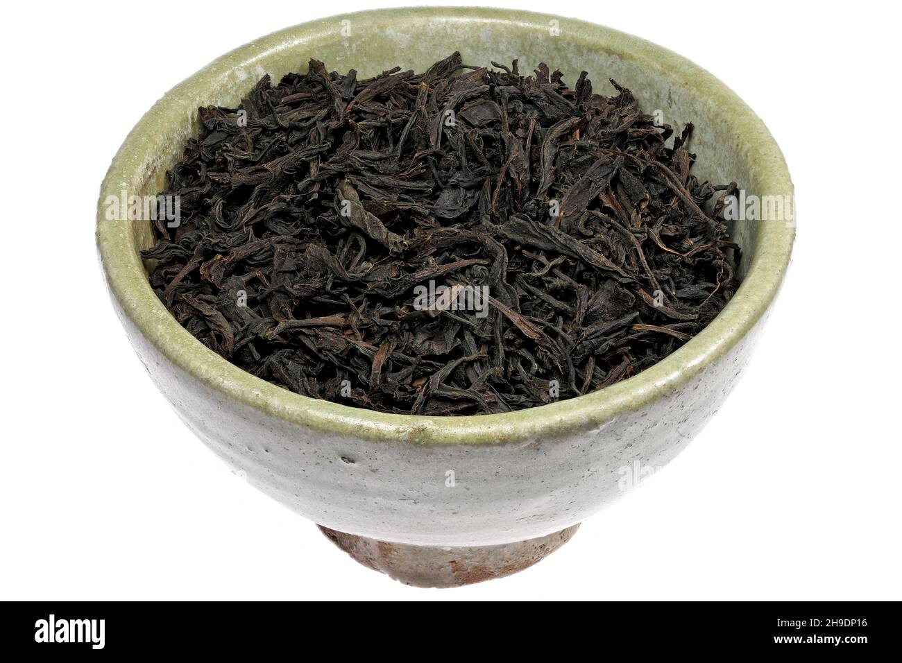 Té negro Ceilán en una vasija de barro de época aislada sobre fondo blanco Foto de stock
