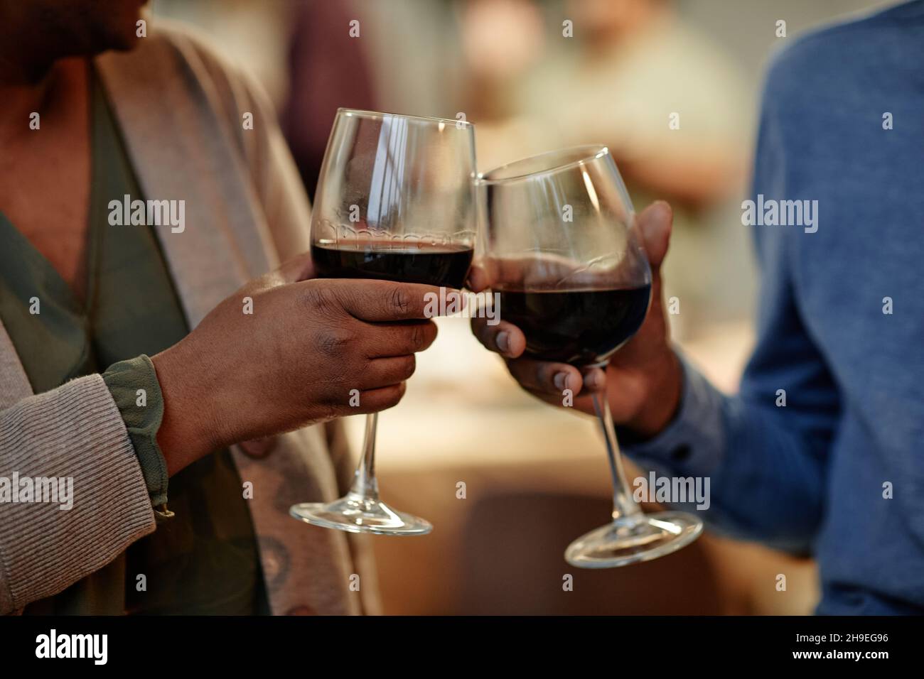 Primer plano de una pareja afroamericana tomando copas de vino mientras disfruta de una cena romántica en casa Foto de stock