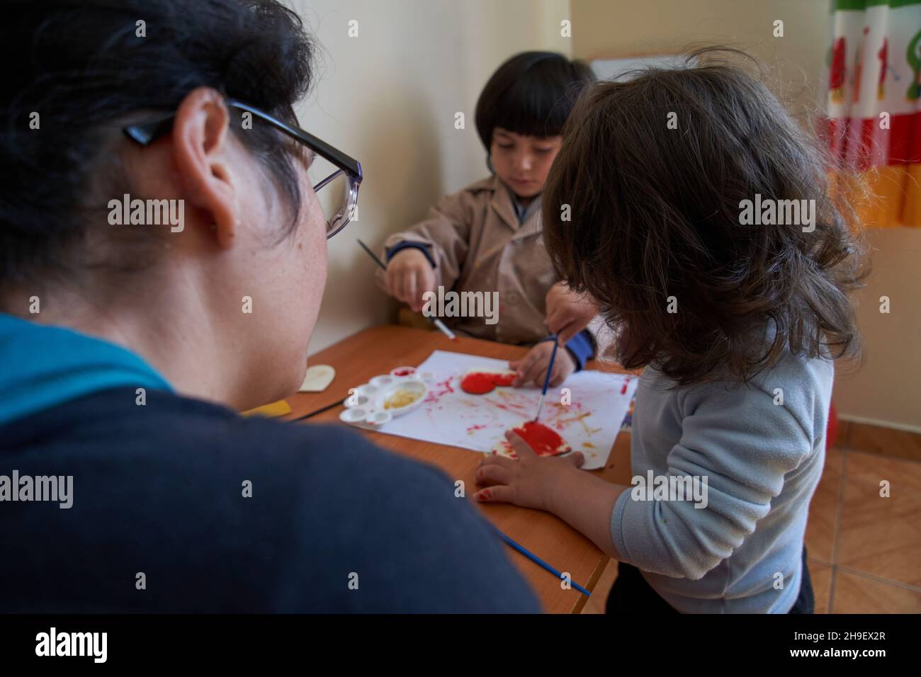 Corazones de pintura preescolar. La madre y los niños pintan juntos. Sesión de arte Foto de stock
