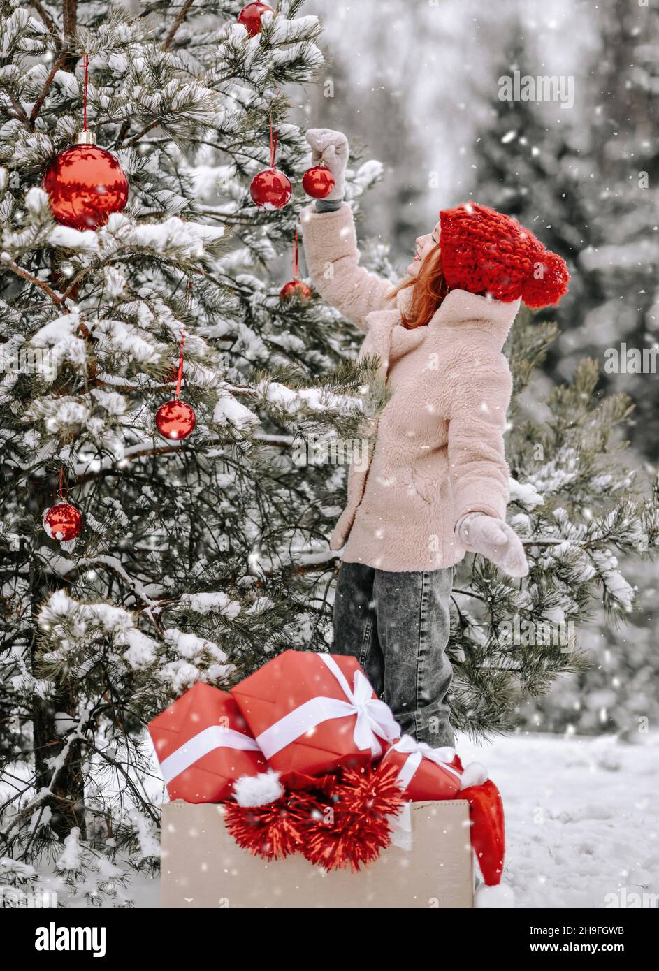 Joven feliz bonita mujer en ropa de invierno con estilo decora al aire  libre de Navidad de Año Nuevo árbol abeto con bolas rojas Fotografía de  stock - Alamy