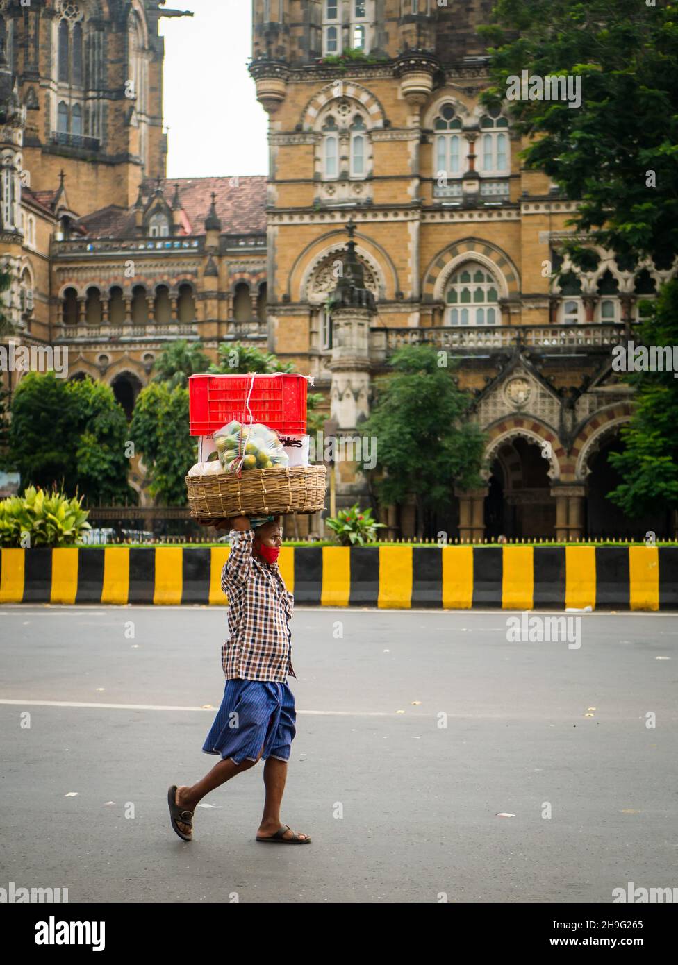 MUMBAI, INDIA - 2 de octubre de 2021 : Portero no identificado que usa una máscara covid-19 que transporta el carro de frutas en la estación CST, Mumbai Foto de stock