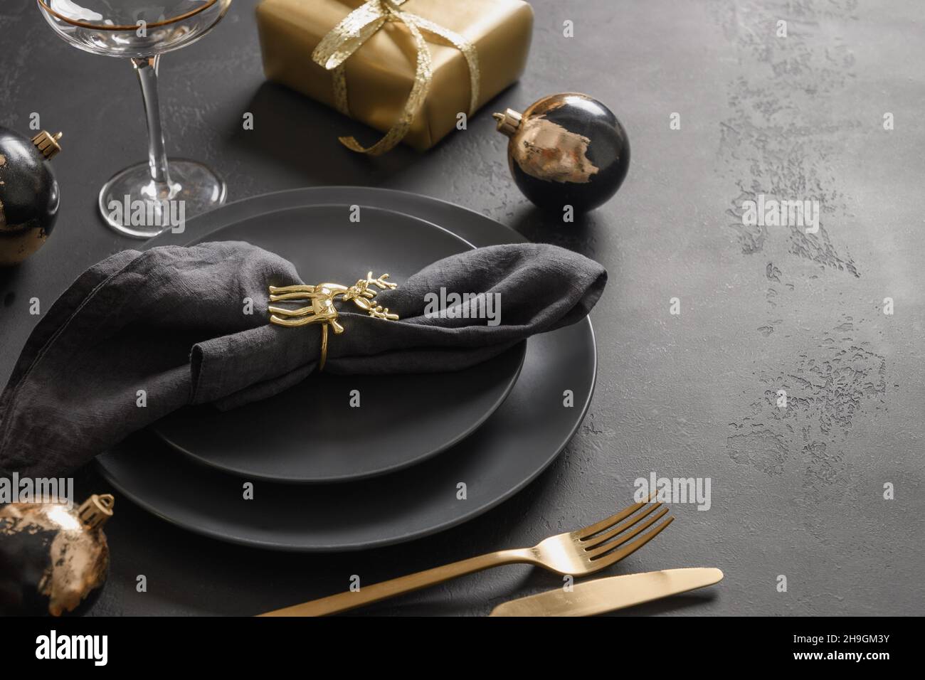 Mesa de Navidad con platos negros oscuros, anillo de ciervo dorado