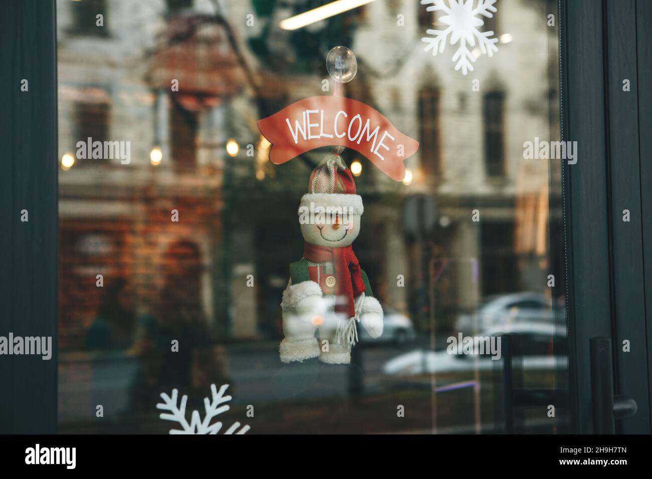 Decoración navideña en la puerta del café con la inscripción Bienvenido. Celebración de Navidad, Año Nuevo y concepto festivo. Foto de stock