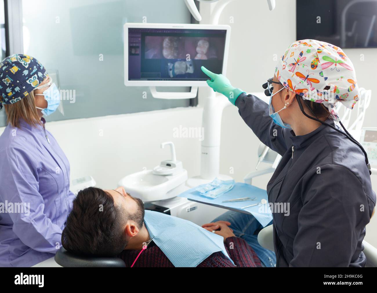 Inspección con una macro cámara dental y muestra el resultado en el monitor. Una joven dentista que trata los canales de la raíz en la clínica dental. Hombre paciente Foto de stock