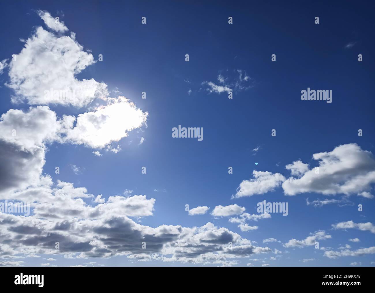 Sol escondido por una nube en un cielo con nubes y claros Foto de stock