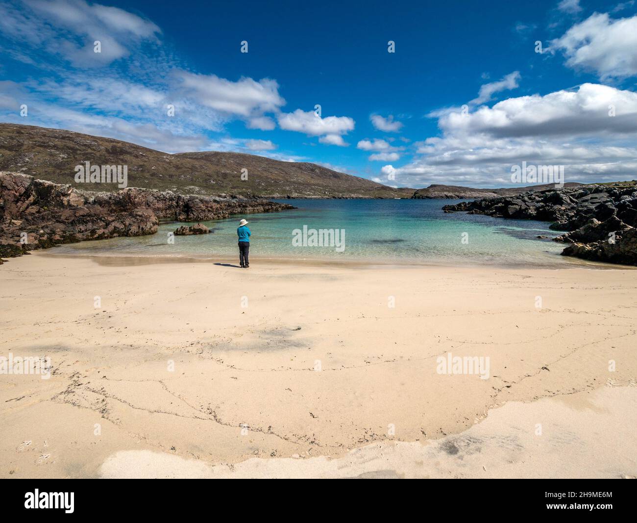 Solitaria mujer de vacaciones / turista de pie en la ensenada de arena de la playa de Hushinish, Isla de Harris, Escocia, Reino Unido Foto de stock