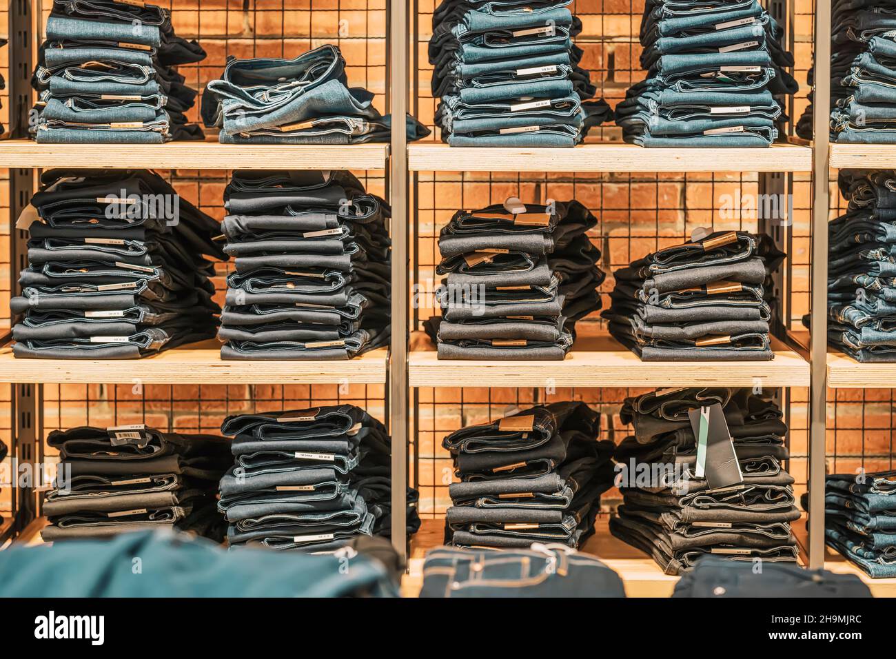 Jeans doblados en estantes de madera, tienda de ropa, centro comercial  moderno. Ropa informal para jóvenes Fotografía de stock - Alamy