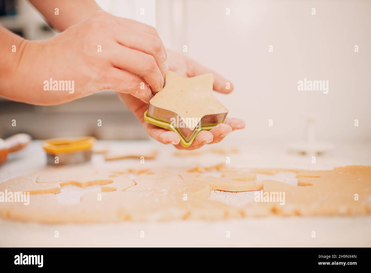 Las manos de la mujer forman moldes cortadores de masa de jengibre y hace deliciosas galletas de jengibre de Navidad. Cocinar y decorar postre de Navidad. Foto de stock