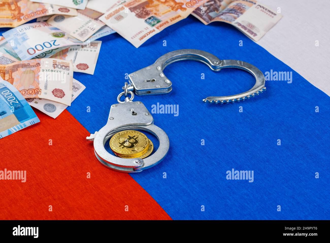 papel ruso rublos moneda y moneda de bitcoin shiner encadenado con esposas en el fondo de la bandera rusa Foto de stock
