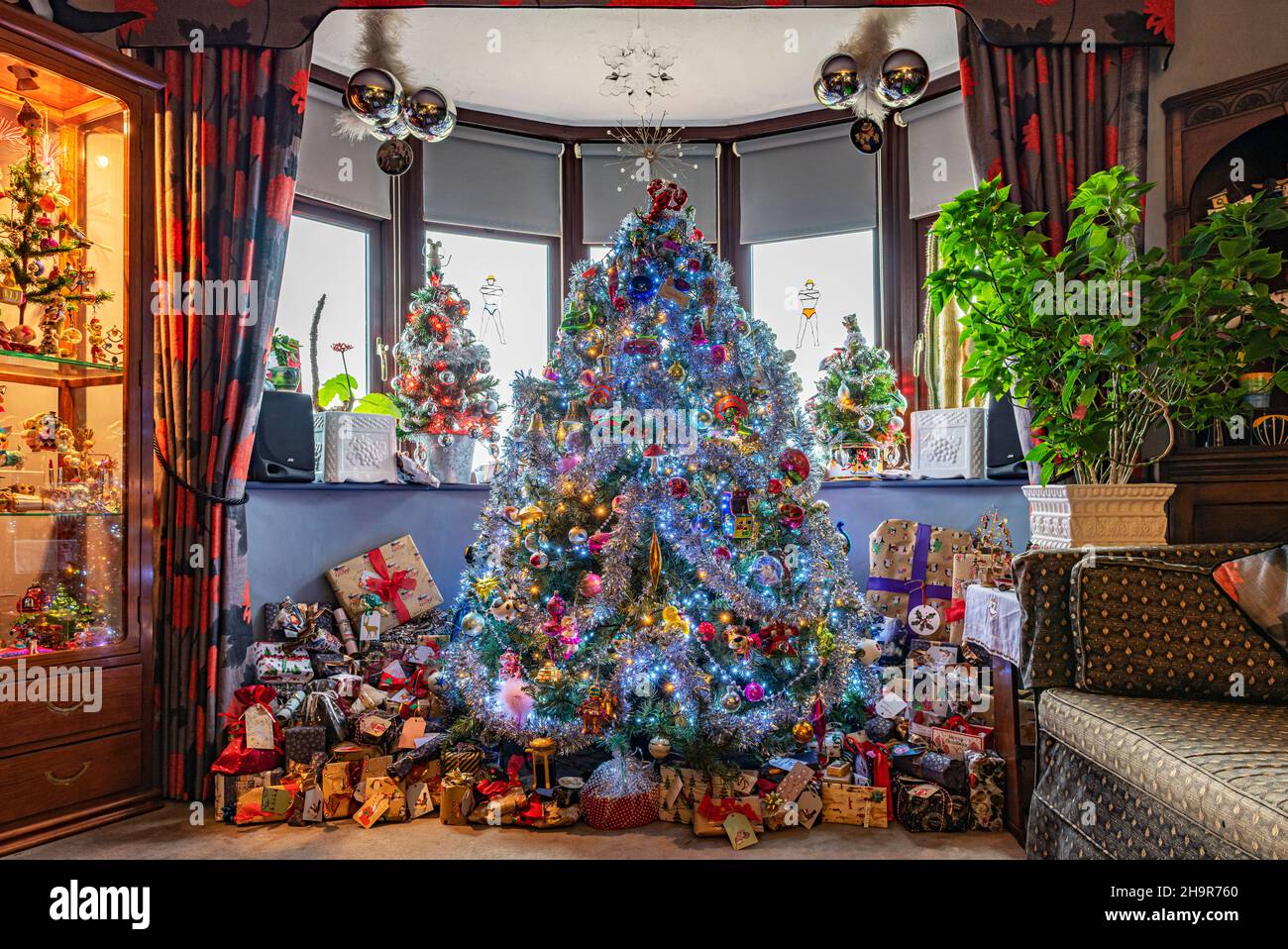 Árbol de Navidad decorado en una habitación rodeada de regalos Foto de stock