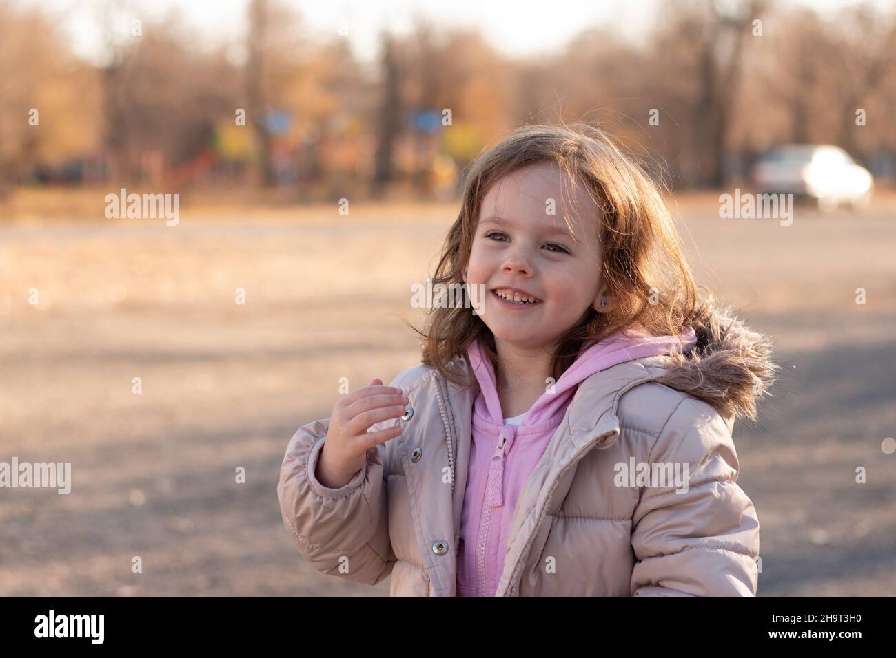 niña de pelo rojo en una chaqueta con una capucha esponjosa sonríe al fondo de una calle Fotografía de stock - Alamy