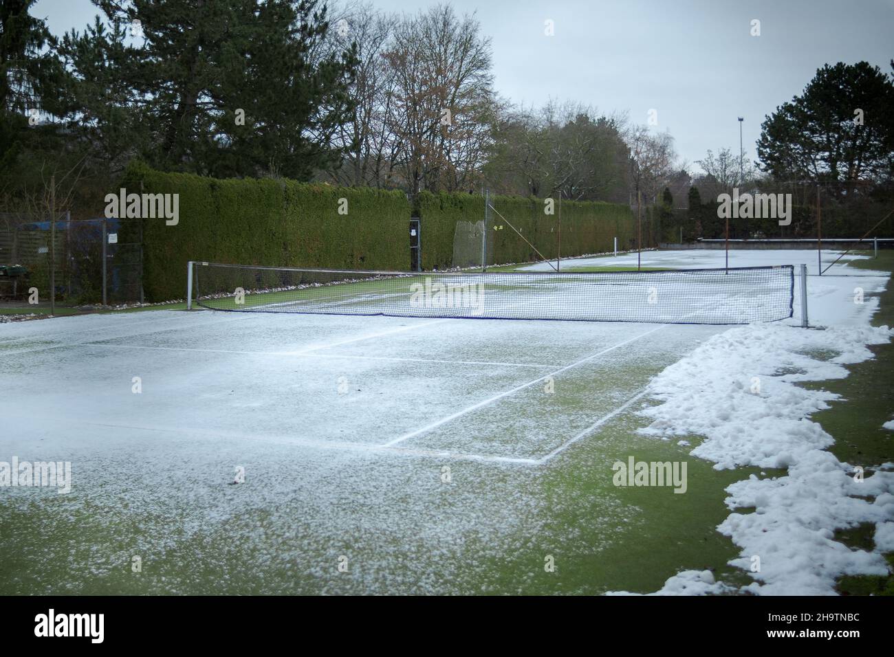 Canchas de tenis de césped vallado en la zona suburbana con nieve en invierno Foto de stock