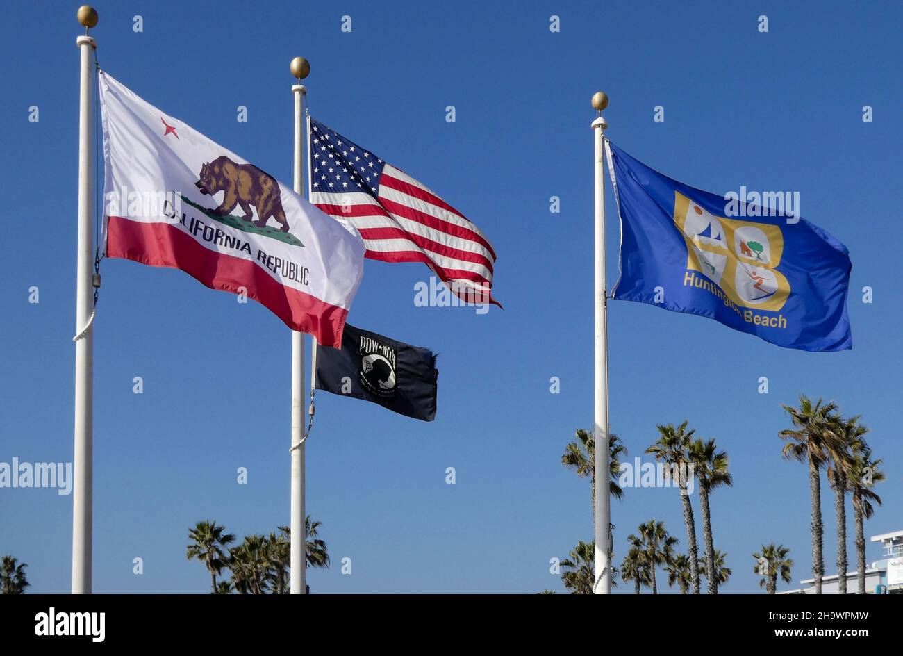 Cuatro banderas en postes de bandera volando en Huntington Beach, California Foto de stock