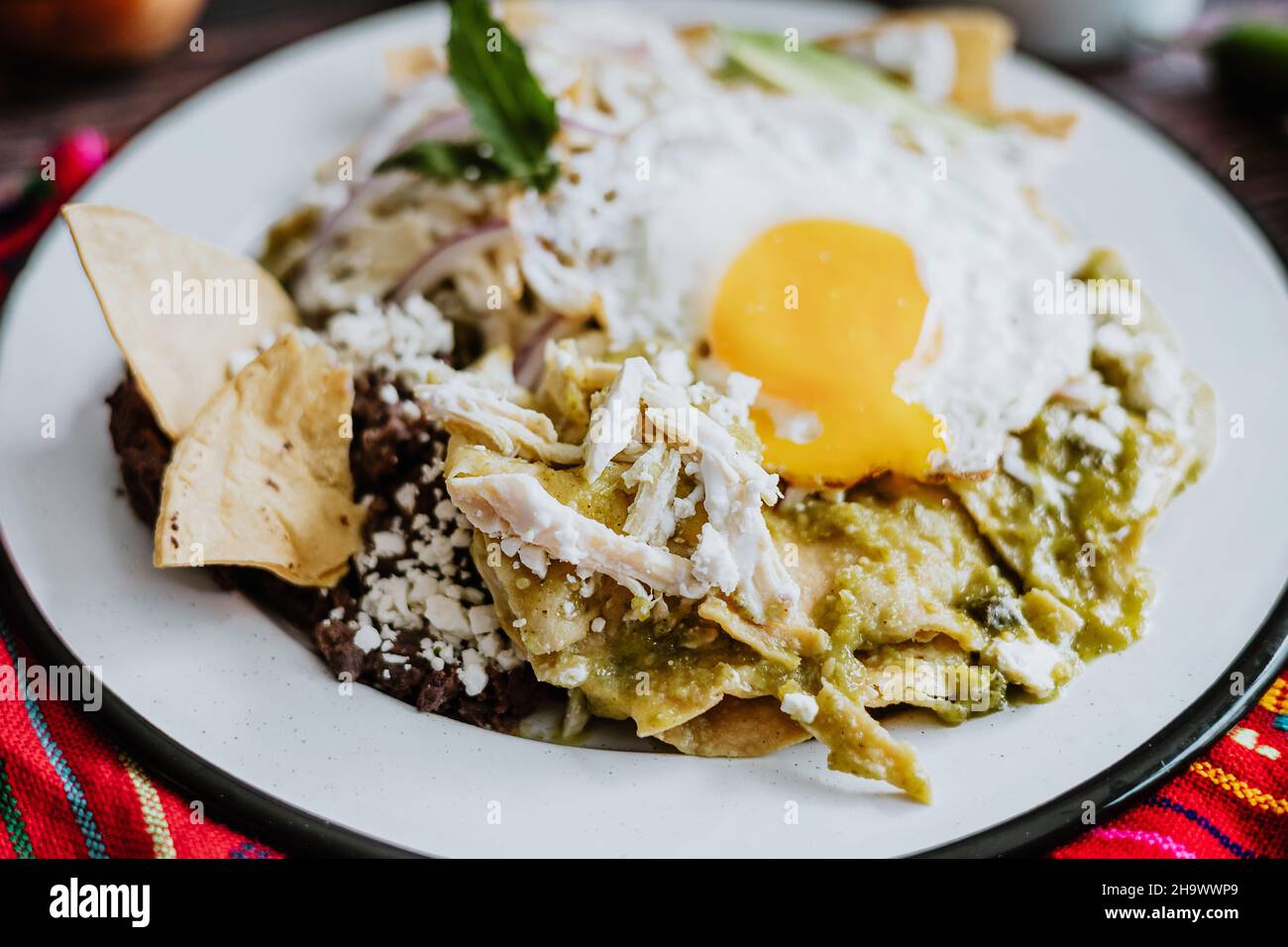Chilaquiles verdes mexicanos con huevo frito, pollo y salsa picante de verde  tradicional desayuno en México Fotografía de stock - Alamy