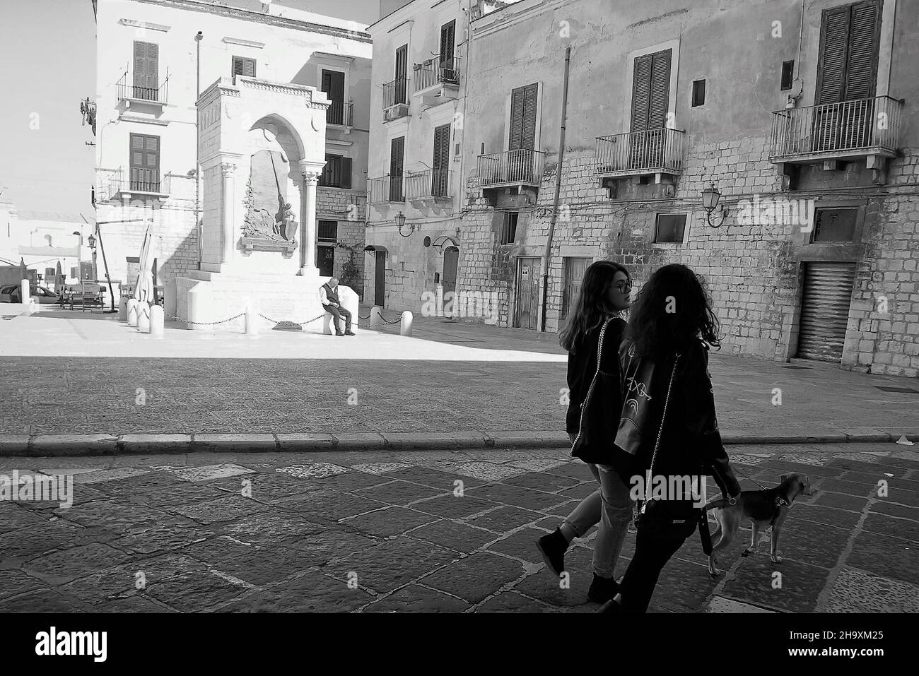 Matera,Basilicata;10/14/2017:Dos chicas por la mañana en la calle de la ciudad de Matera, caminan por el perro. Foto de stock