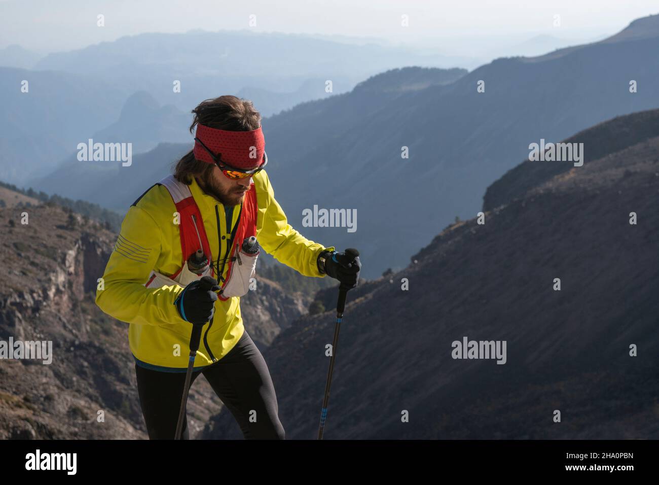 Un hombre vestido de amarillo usando postes sube hasta Pico de Orizaba Foto de stock