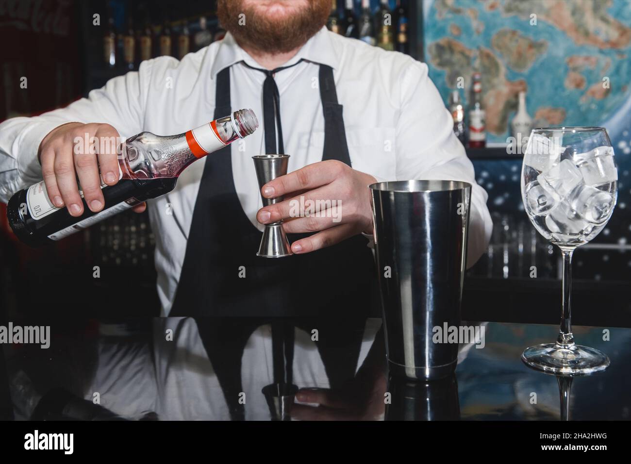 Las manos de un barman profesional verter jarabe rojo en un vaso medidor de  jigger, junto a una herramienta de metal para preparar y remover berechos  alcohólicos Fotografía de stock - Alamy