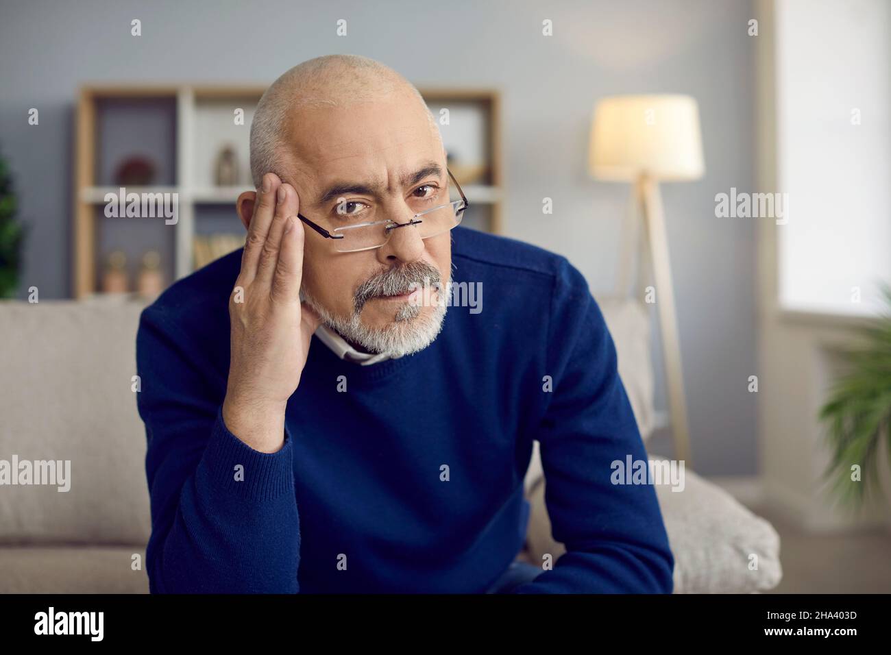Retrato de un hombre mayor serio en gafas sintiéndose escéptico y dudoso sobre su idea Foto de stock