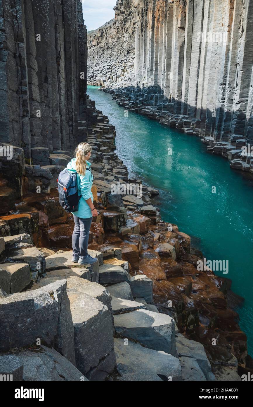 mujer excursionista con mochila disfrutando del cañón studlagil. columnas basalt jokulsa únicas y un río bru. espectacular escena al aire libre de islandia, europa. belleza de fondo de concepto de naturaleza. Foto de stock