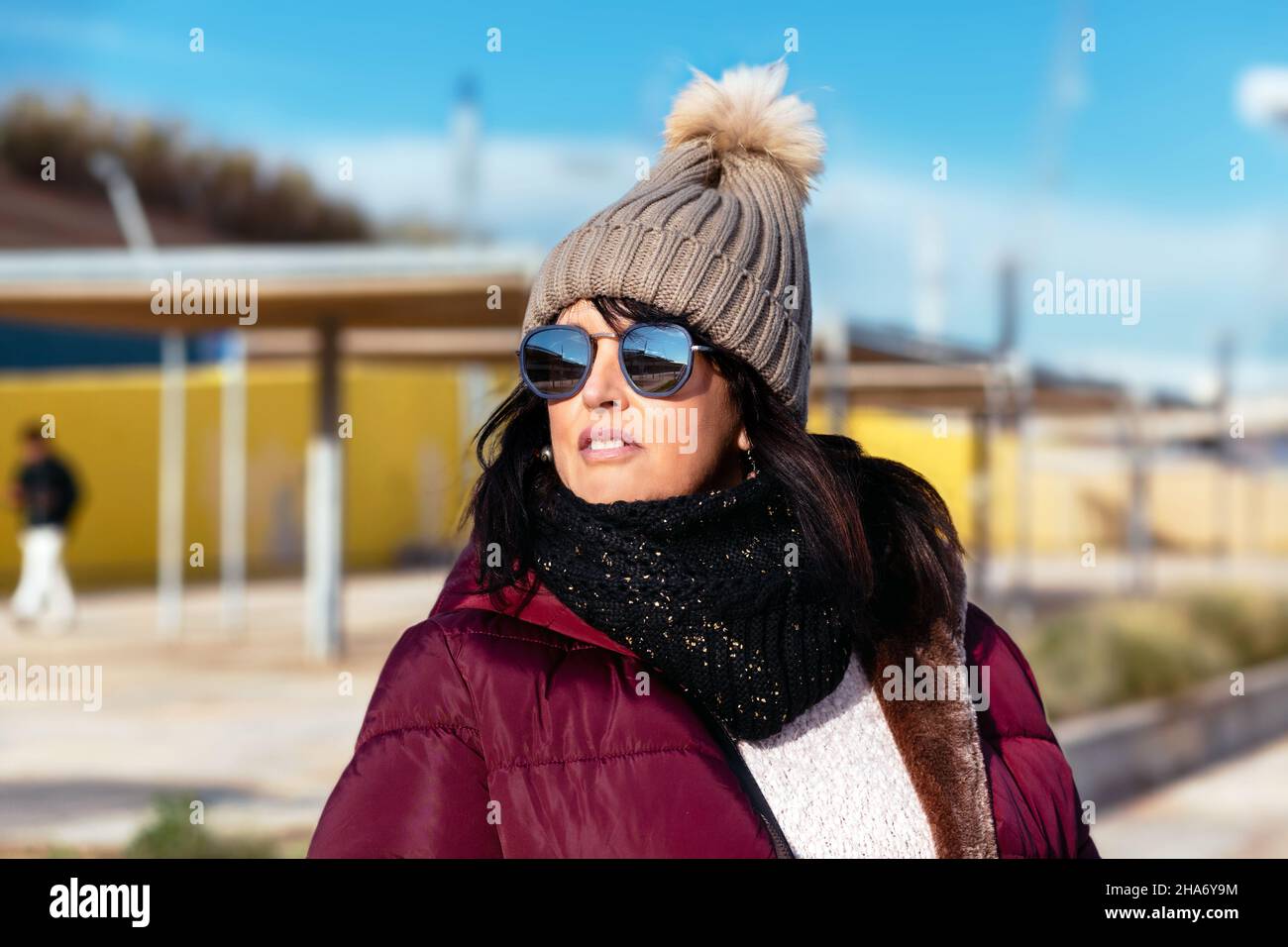retrato de una mujer con gafas de sol y gorra de lana en un soleado día de otoño caminando por la ciudad Foto de stock
