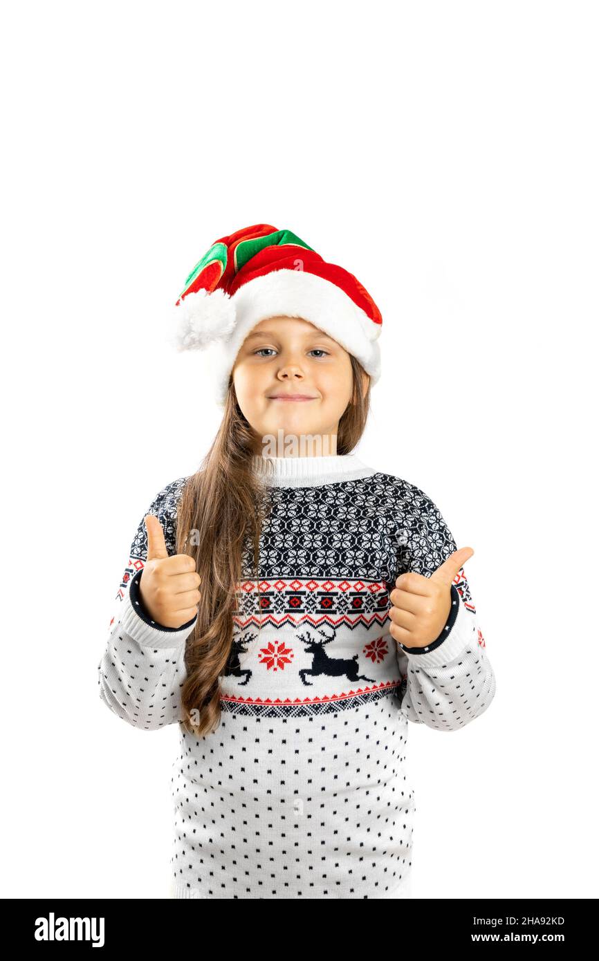 Retrato completo de chica encantadora en jersey de Navidad blanco con reno y sombrero enano que da pulgares, aislado sobre fondo blanco Foto de stock